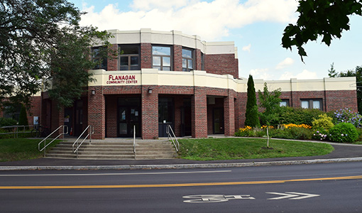 Brick building with green shrubbery and trees.