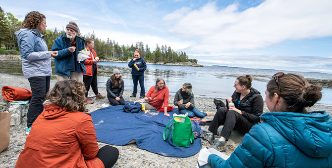 Group of people stand and sit on the beach having a picnic