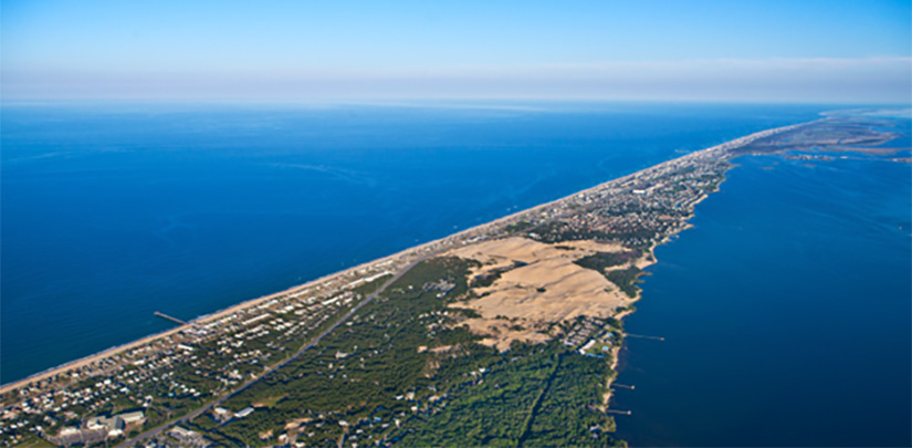 A thin strip of green and brown land surrounded by water on both sides.