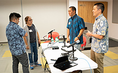 Four people talk on either side of a table.