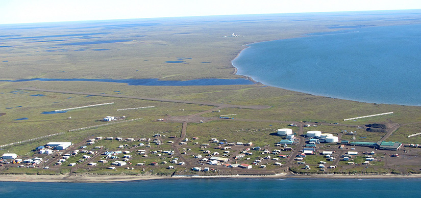 An aerial view of buildings on a peninsula with water on two sides and sky.