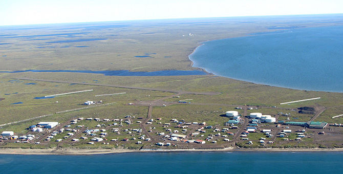 An aerial view of buildings on a peninsula with water on two sides and sky.