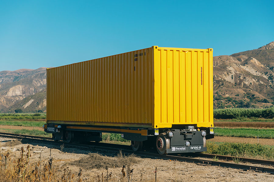 A freight car on a train track in a remote, mountainous area.