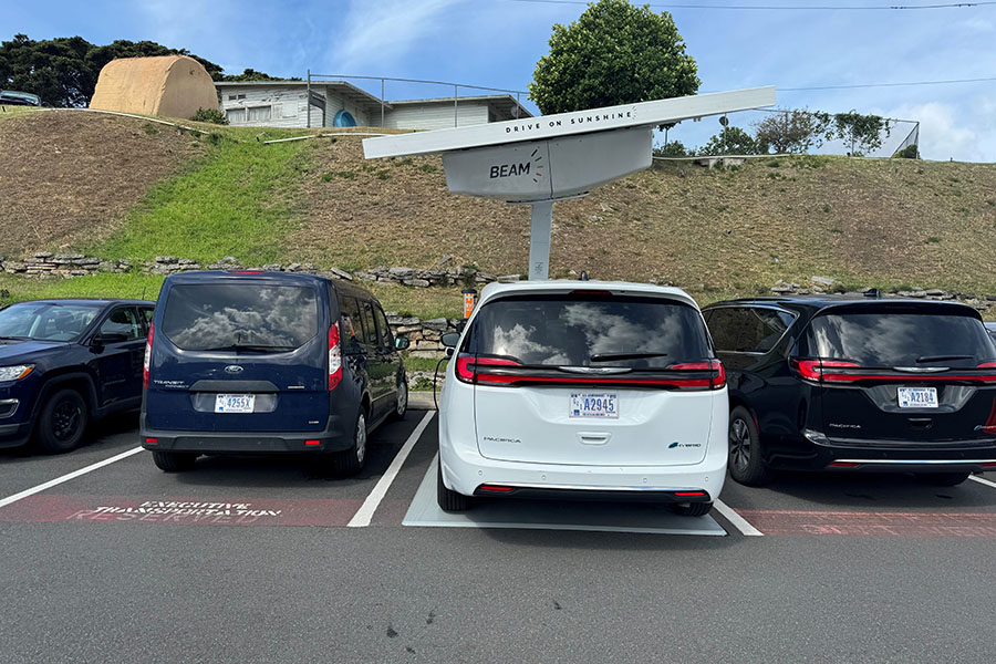 A solar-powered, EV charging station in use at a parking lot.