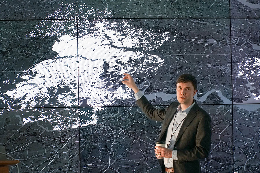 A researcher pointing at a large 2D map visualization.