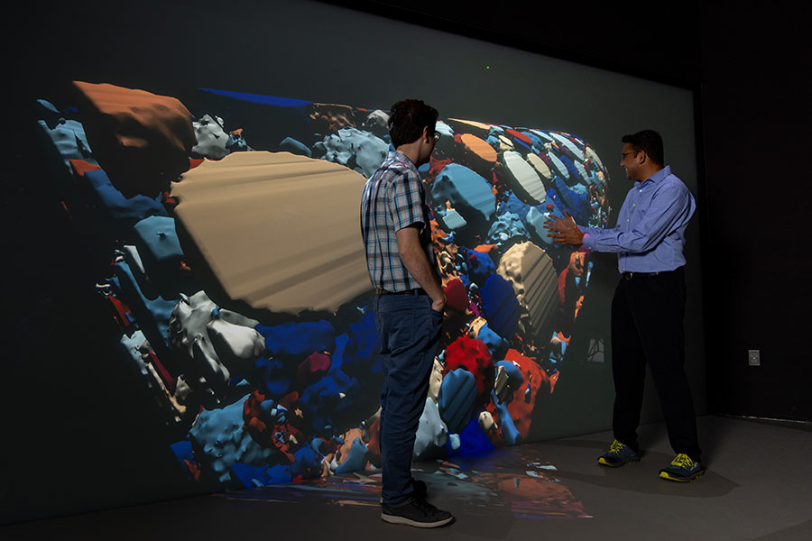 Two researchers looking at a large, 3D visualization of nanoparticles.