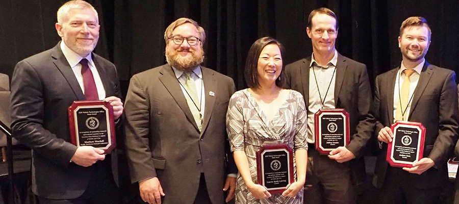 A group of people smiling while holding awards.