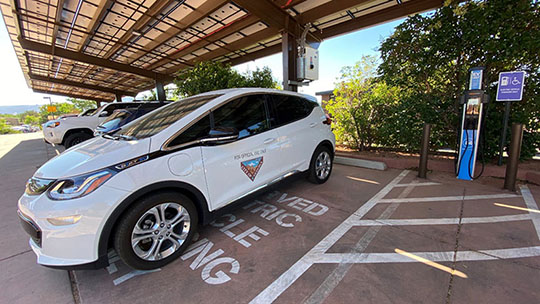 A white EV, part of a fleet owned by the city of Sedona, parked in a covered parking area.