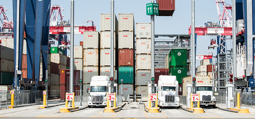 Automated electric stacking cranes load cargo containers onto waiting trucks at the Port of Long Beach.