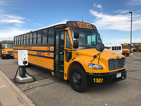 An electric school bus next to a charging station