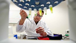 Photo of person in laboratory setting with an array of vials in round holder.