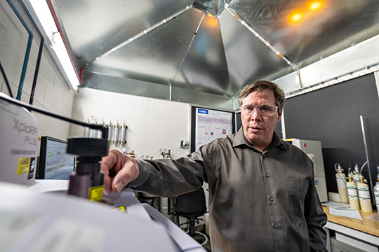 A researcher wearing safety glasses working in a batteries lab.