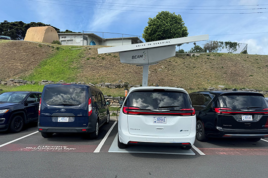 An EV plugged into a charger powered by a solar array mounted above the charging spot.