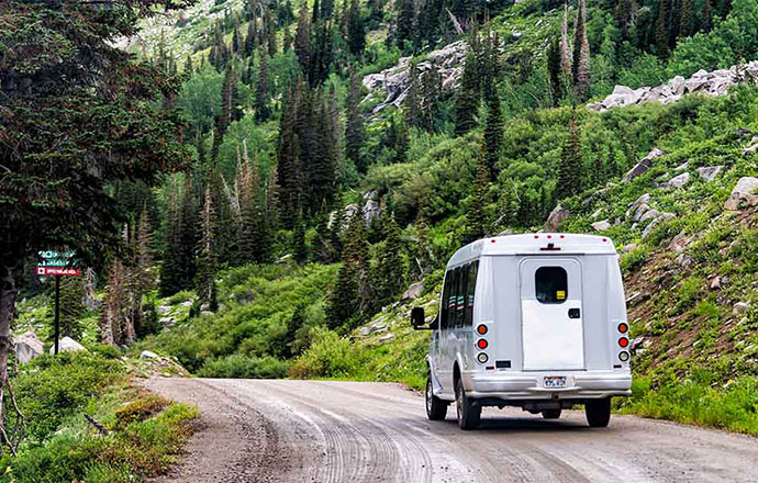 A shuttle bus on dirt road in summer in the Wasatch mountains of Utah.