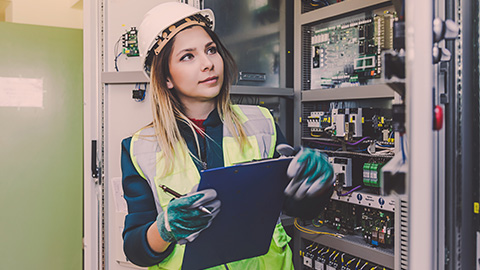 Woman wears safety gear while examining computer electronics inside laboratory.