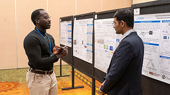 Researcher presenting a poster to a colleague at a NAWI event