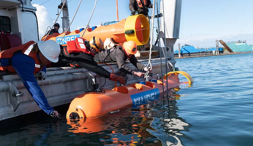 Reserachers holding an NREL buoy steady while it is being unshackled for a ballast text in the Homer harbor in Alaska.