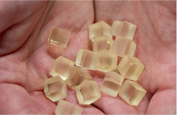 Hands hold cubes of the plant-based resin