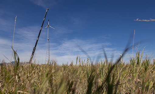 Wind turbine next to a crane out in a field