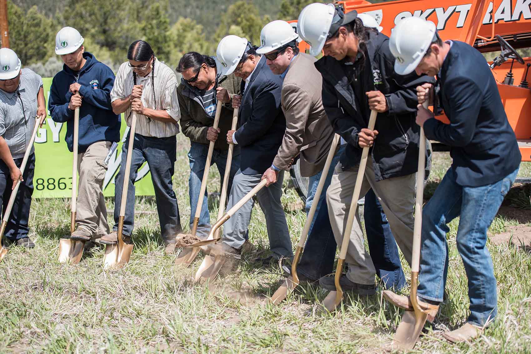 Group of people stand holding shovels to start digging in the ground.